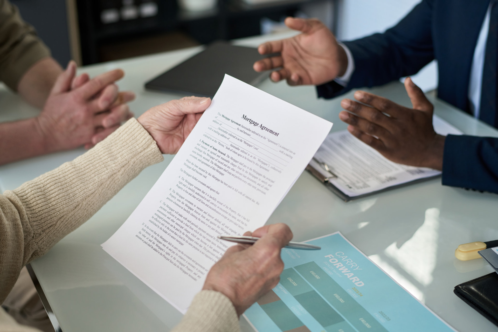 Attorney reviewing a mortgage agreement with clients at a settlement table