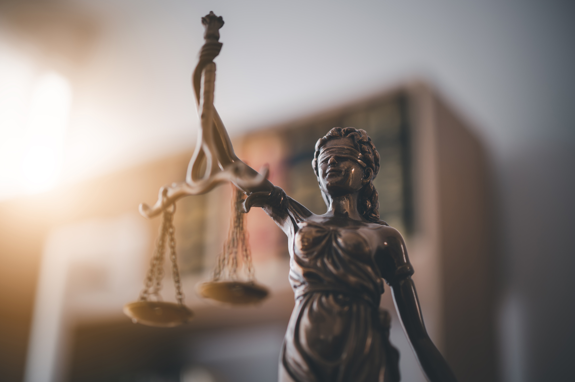 Statue of Lady Justice holding balanced scales in a law office